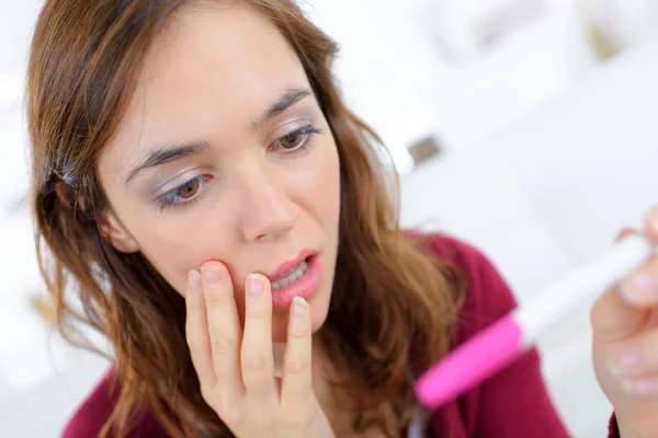 Anguished woman looking at pregnancy tester Royalty Free Stock Photos