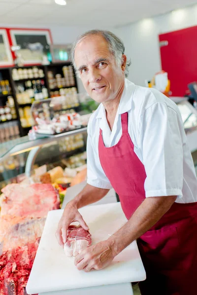 Butcher at counter and bacon — Stock Photo, Image