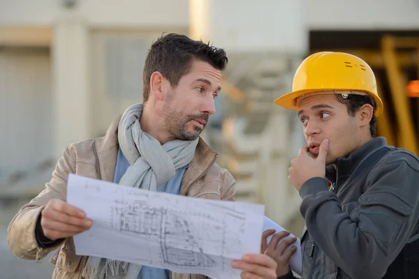 Arquiteto masculino com trabalhador discutindo no canteiro de obras — Fotografia de Stock