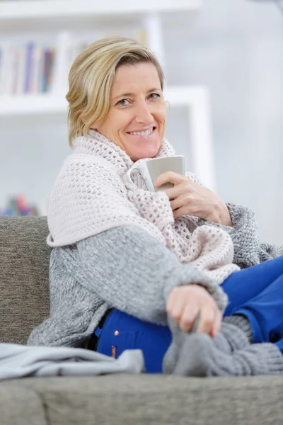 Schöne kranke Frau sitzt zu Hause auf dem Sofa und lächelt — Stockfoto