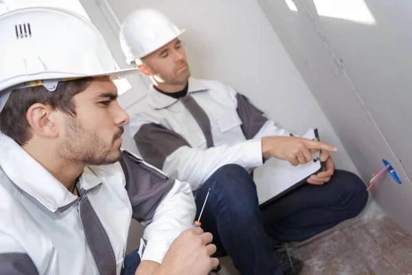 Aannemer manager wijzend op het elektrisch vermogen op de muur — Stockfoto