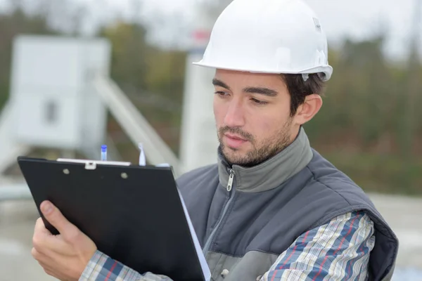 Männlicher Architekt mit Bauplänen beim Lesen von Klemmbrettern im Freien — Stockfoto