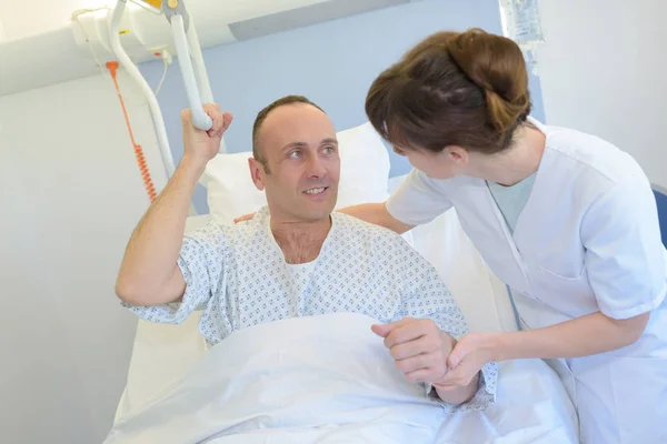 Enfermera ayudando al paciente a levantarse de la cama — Foto de Stock