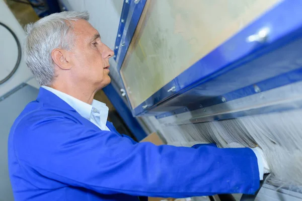 Old mechanician workin on factory machinery — Stock Photo, Image