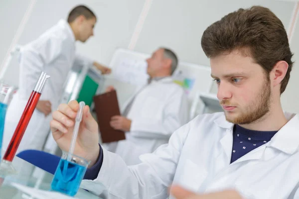 Laboratuvarda sıvı reaksiyonunu gözlemleyen genç bilim adamı — Stok fotoğraf