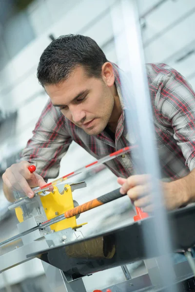 Fabrikarbeiter überprüft in Werkstatt die Geradlinigkeit von Metallplanken — Stockfoto