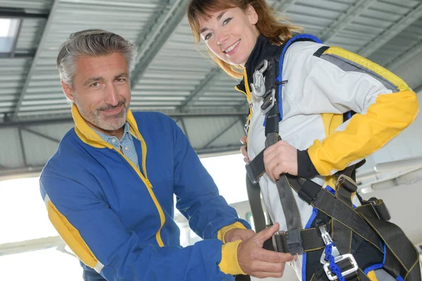 Hombre adjuntando arnés en paracaidista femenino —  Fotos de Stock