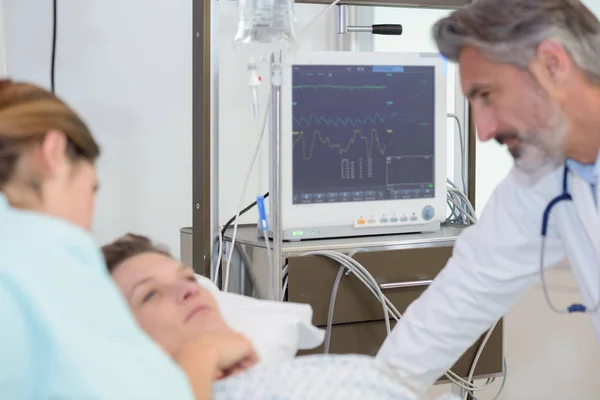 Arzt und Krankenschwester stehen um einen Patienten im Krankenhaus — Stockfoto