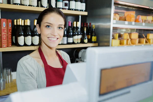 Beautiful female food store employee at the cashier smiling — Stock Photo, Image