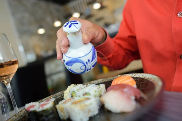 Person gießt Gewürz auf Sushi — Stockfoto