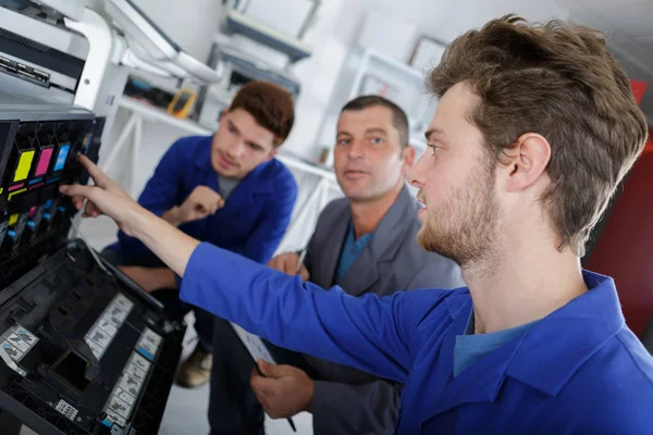 Ученики мужского пола пытаются починить офисный принтер — стоковое фото