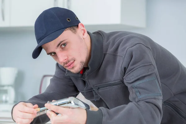 Bonito jovem encanador fixação torneira no cleints casa — Fotografia de Stock