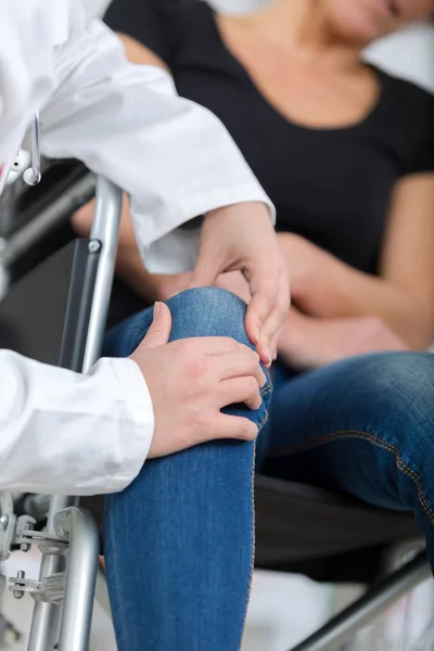 Female handicapped suffers pain in her knee doctor ausculting — Stock Photo, Image
