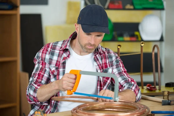 Industrieklempner schneidet ein Kupferrohr mit — Stockfoto