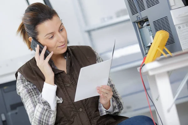 Technikerin liest Bedienungsanleitung und telefoniert — Stockfoto