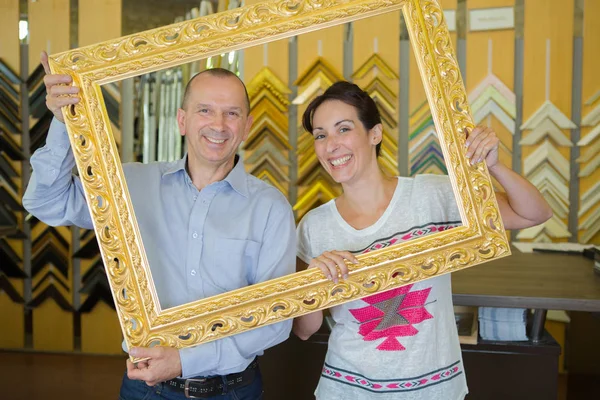 Couple in a cute picture holding a wooden frame — Stock Photo, Image