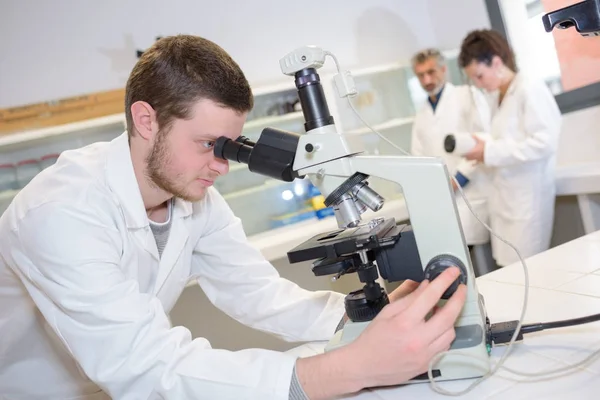 Man looking through a microscope — Stock Photo, Image