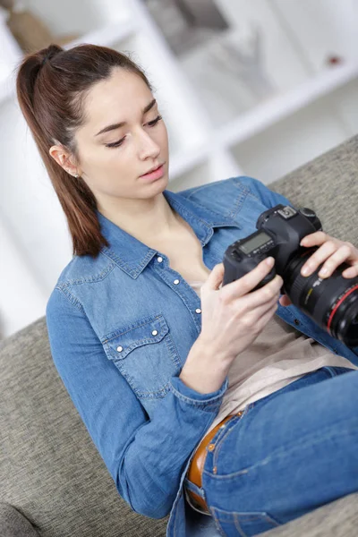 Fotógrafa con cámara en el sofá de la habitación —  Fotos de Stock