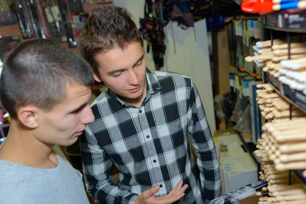 Comprador masculino elegir palos de tambores en la tienda de música — Foto de Stock