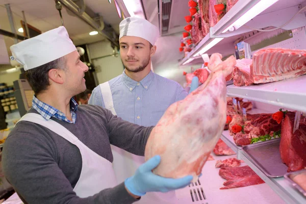 Učí mladou jak prodávat maso řezník — Stock fotografie