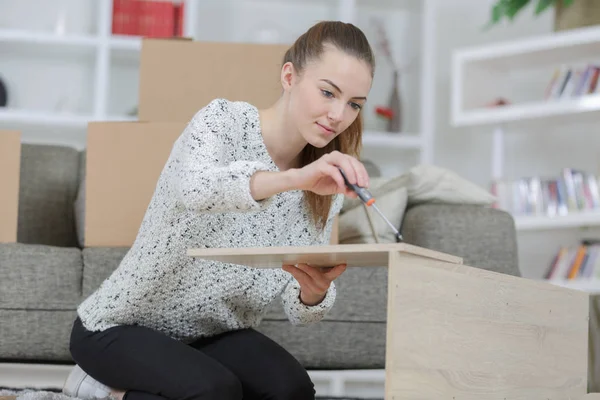 Женщина собирает мебель на дому — стоковое фото
