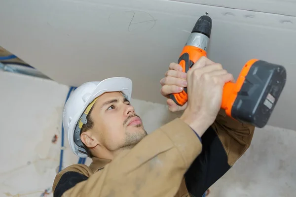 Giovane maestro con un trapano imposta soffitto in cartongesso — Foto Stock