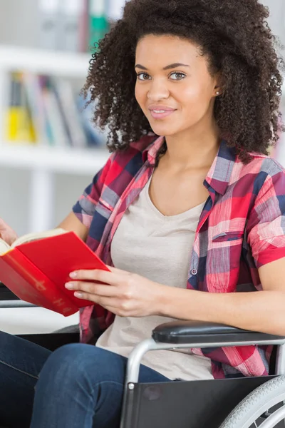 Estudante com deficiência sorridente em livro de leitura de biblioteca na universidade — Fotografia de Stock