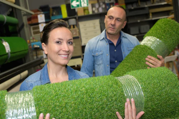 Man and woman holding rolls of artificial turf — Stock Photo, Image