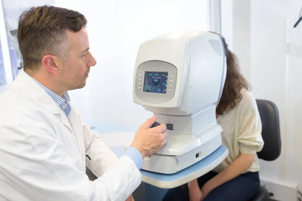 Mujer mirando la máquina de la prueba del ojo en la clínica de oftalmología —  Fotos de Stock