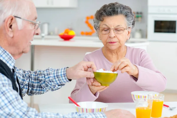Feliz pareja de ancianos discutiendo mientras desayunan en la mesa — Foto de Stock