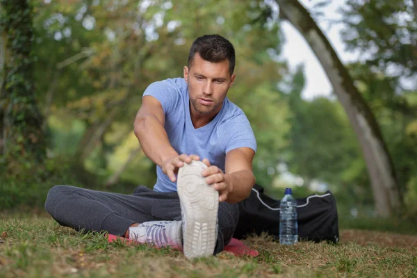 Man stretching before running on a forest trail — Stock Photo, Image