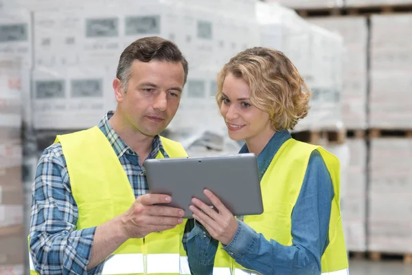 Gerente mostrando tableta al trabajador en un almacén — Foto de Stock