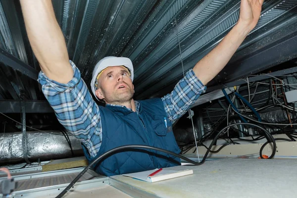 Eletricista instala fiação no teto — Fotografia de Stock