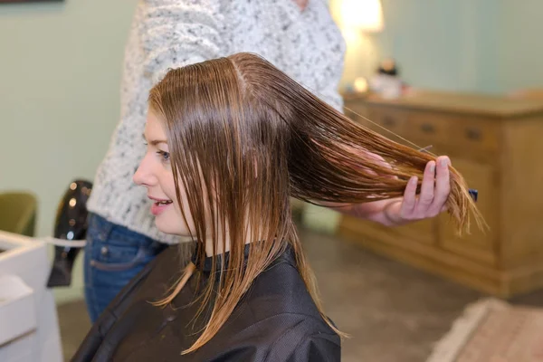Giovane bella donna che si fa tagliare i capelli dai parrucchieri — Foto Stock