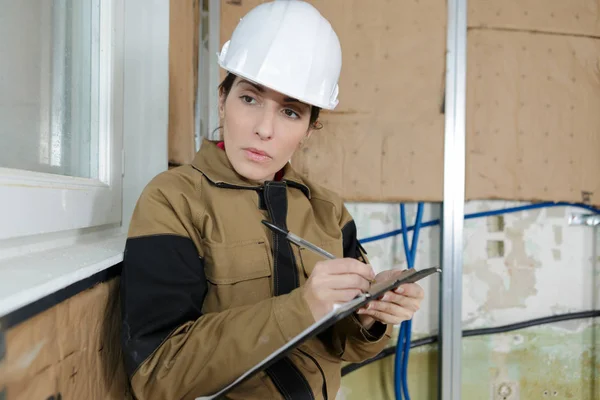 Kvinnlig civilingenjör tar anteckningar på byggarbetsplats — Stockfoto