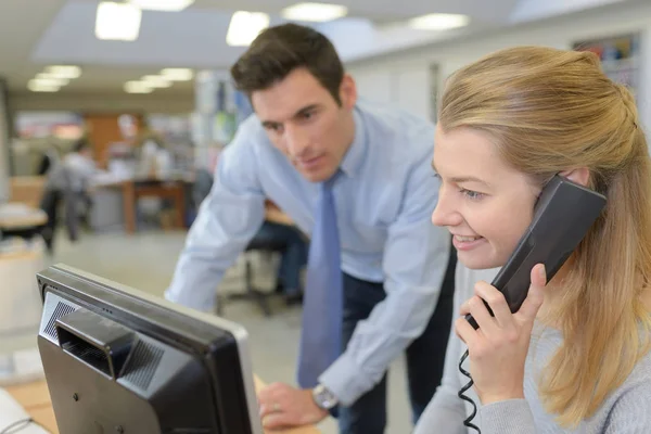 Joven empresaria sonriente usando teléfono fijo en la oficina — Foto de Stock