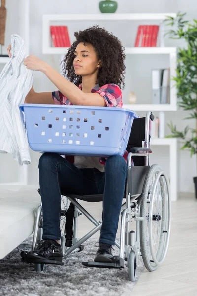 Kobieta na wózku inwalidzkim, sortowanie prania — Zdjęcie stockowe