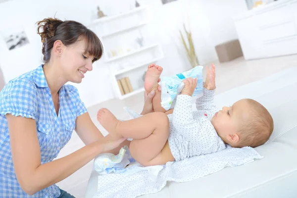 Mother changing diapers of a nine months old baby — Stock Photo, Image