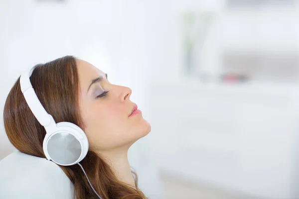 Joven hembra con auriculares relajantes en casa —  Fotos de Stock