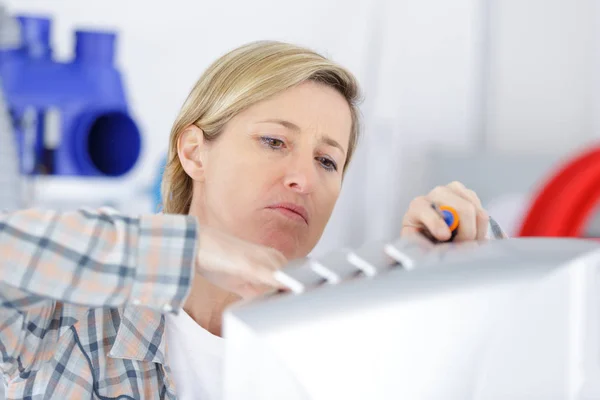 Blond handywoman rengöring fastställande ventilationssystem — Stockfoto