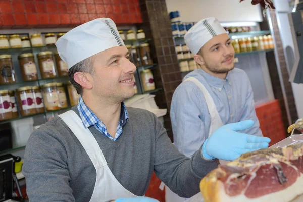 Učí mladou jak prodávat maso řezník — Stock fotografie