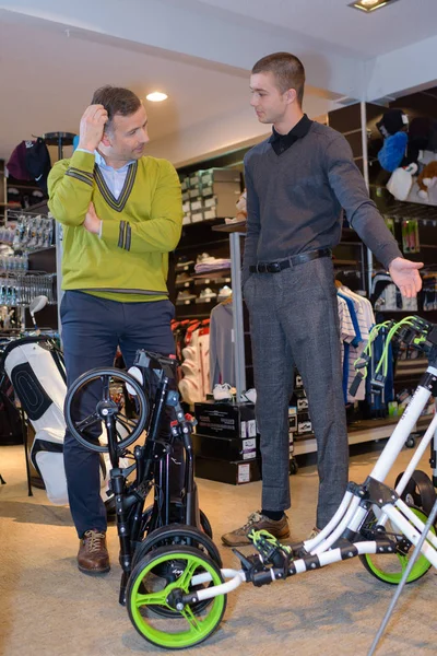 Menino mostrando uma bicicleta para os amigos na loja de esporte — Fotografia de Stock