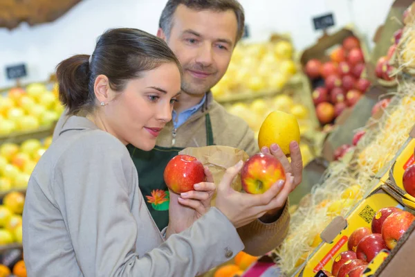 Mujer sonriente eligiendo diferentes frutas en la exhibición de la tienda de alimentos de granja — Foto de Stock