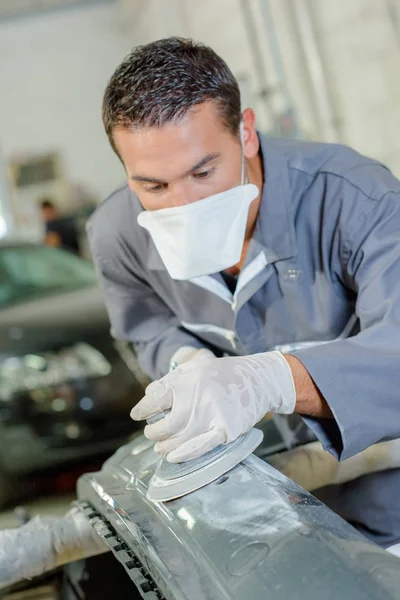 Mechanic sanding car bumper — Stock Photo, Image