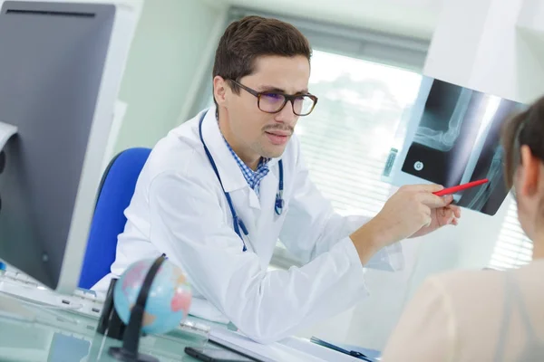 Médico apontando para raio-x em consultório médico — Fotografia de Stock