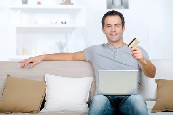 Man with laptop holding its card — Stock Photo, Image