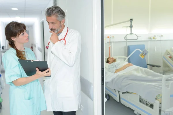 Personale medico in discussione fuori dalla stanza del paziente — Foto Stock