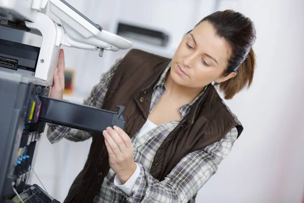 Mulher que verifica a tinta na fotocopiadora — Fotografia de Stock