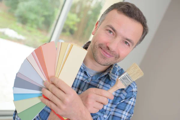 Unga dekoratör holding färgprover och pensel — Stockfoto