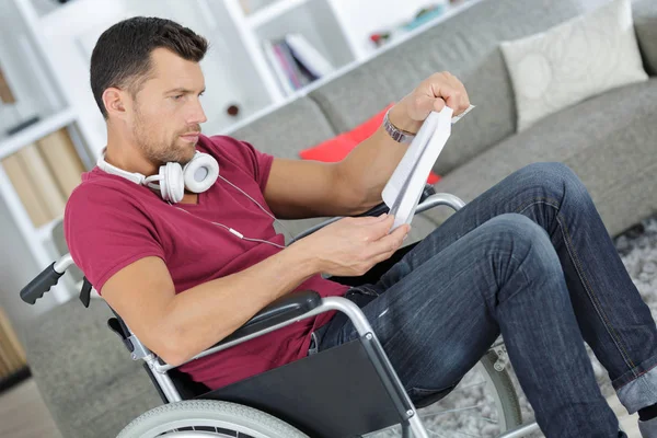 Man på rullstol läser en bok — Stockfoto